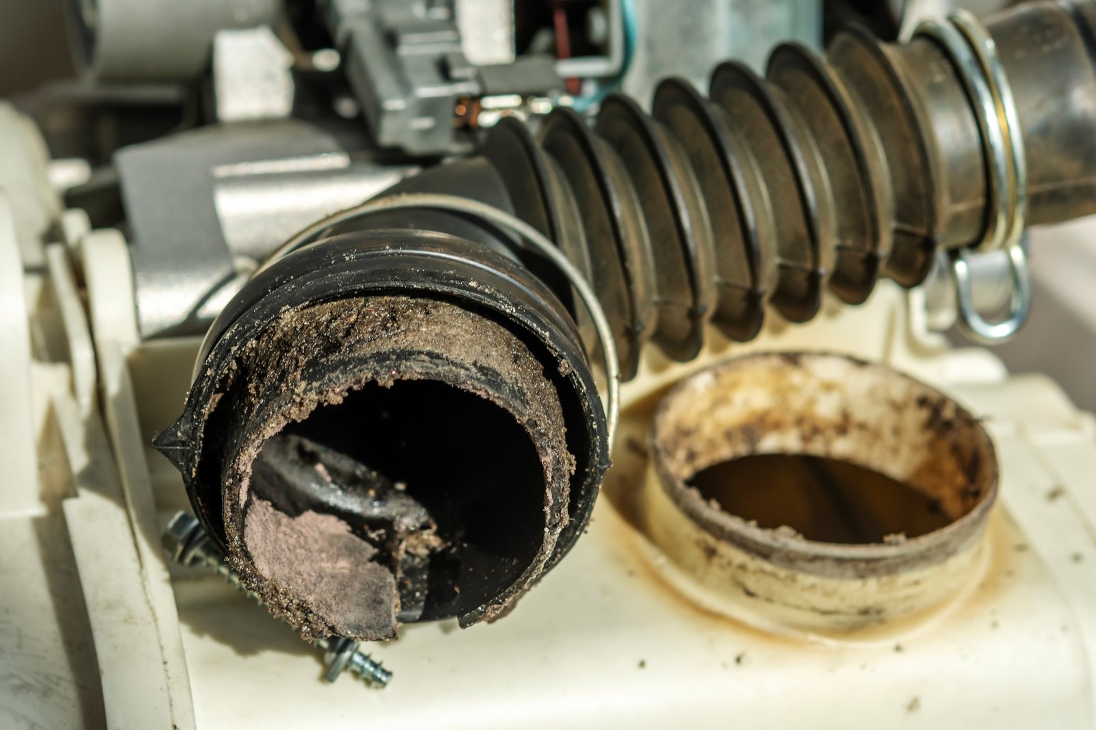 Black washing machine drain pipe with clog. The concept of proper washing machine maintenance.