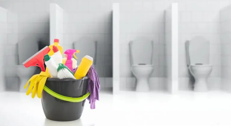 Cleaning supplies in a bucket against blur WC restrooms background.