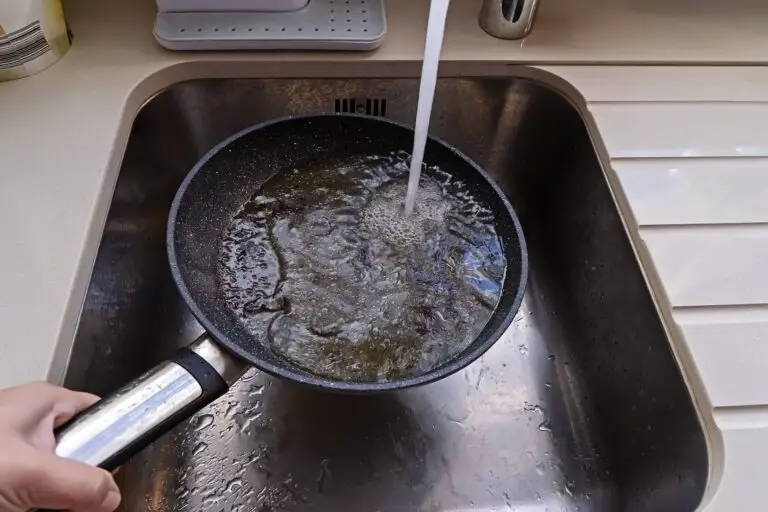 Frying pan with non-stick surface and hot oil under water tap flow in sink. Care kitchenware concept