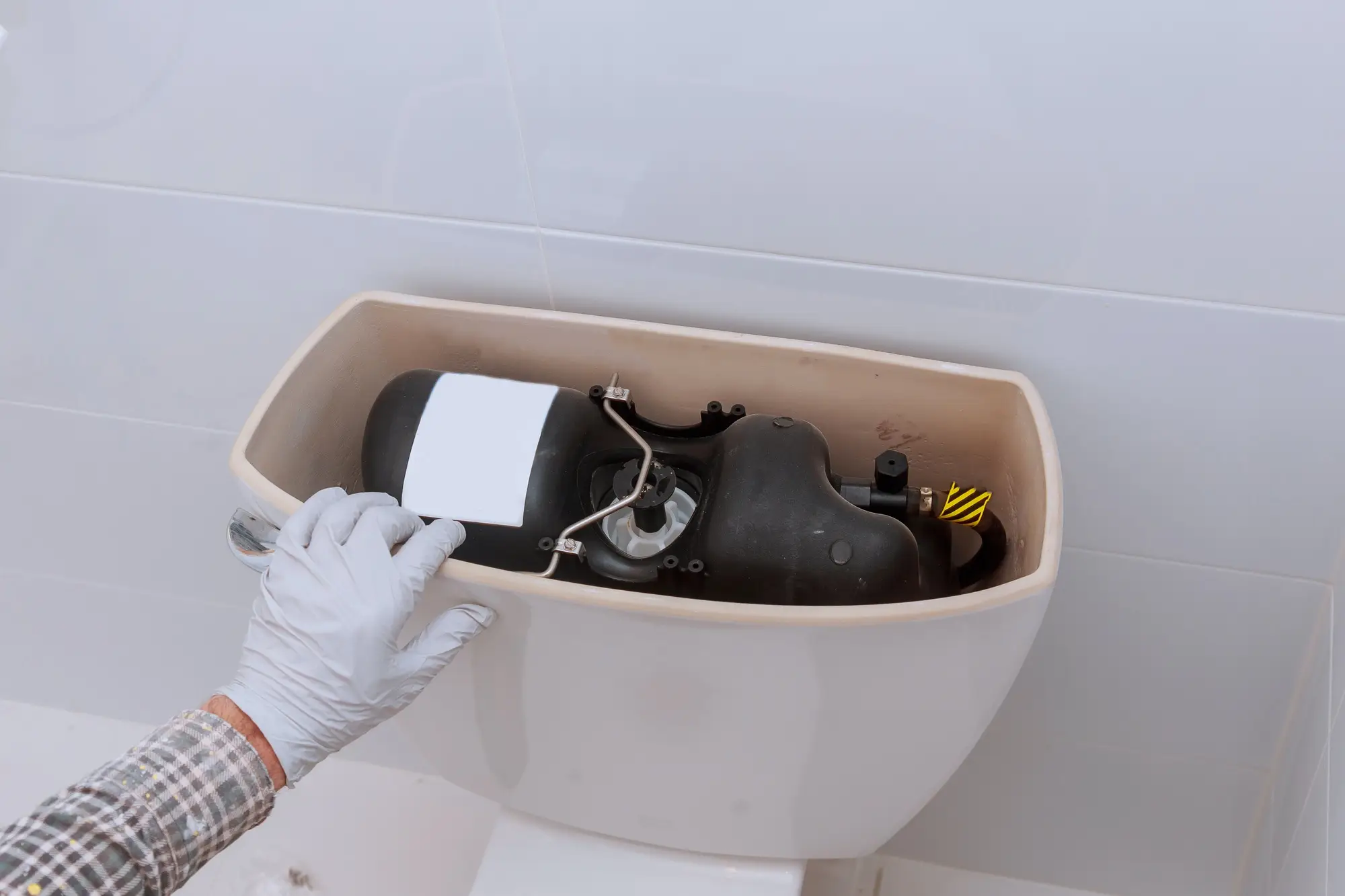 Plombier réparant une chasse d'eau dans une salle de bain